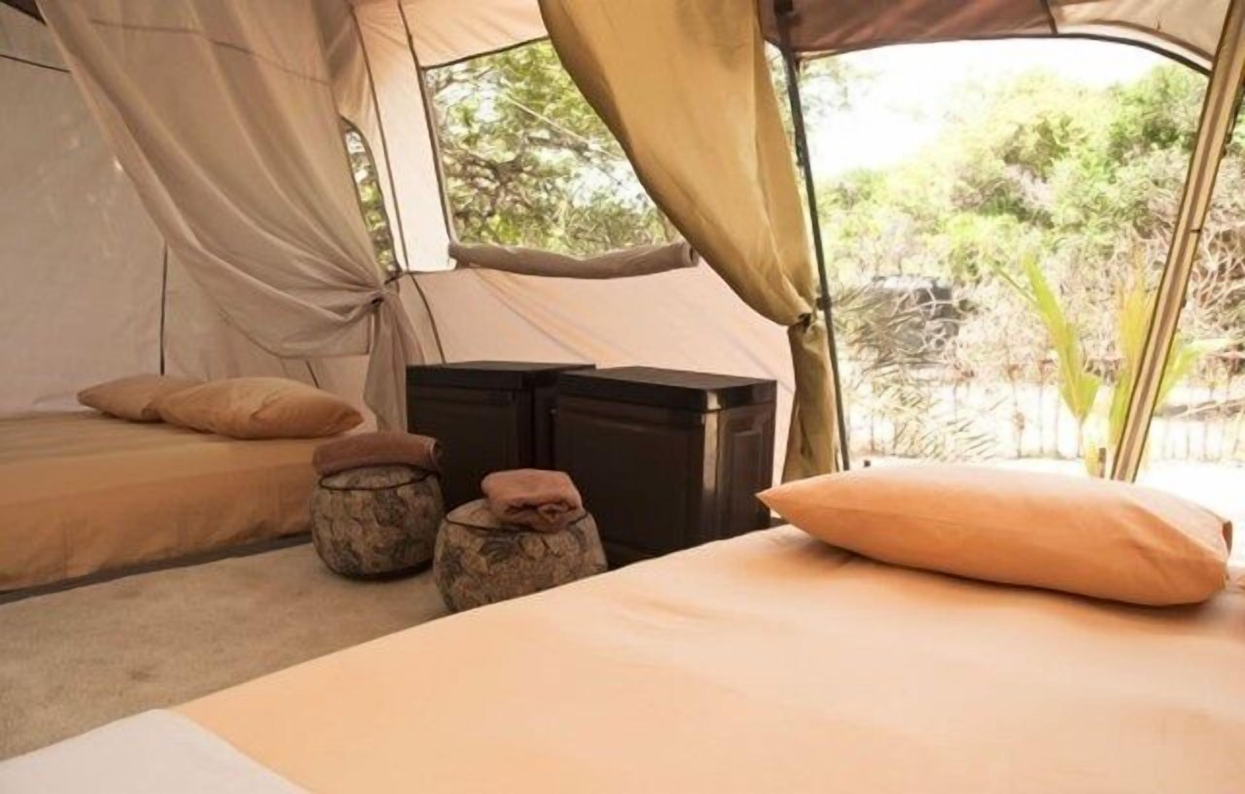 A tent with a bed, pillows, and storage bins.