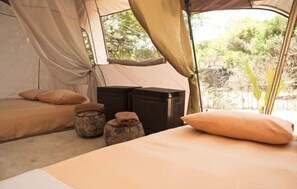Una carpa con cama, almohadas y contenedores de almacenamiento.