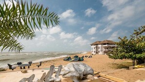A beach with a building, a palm tree, and a lifeguard stand.