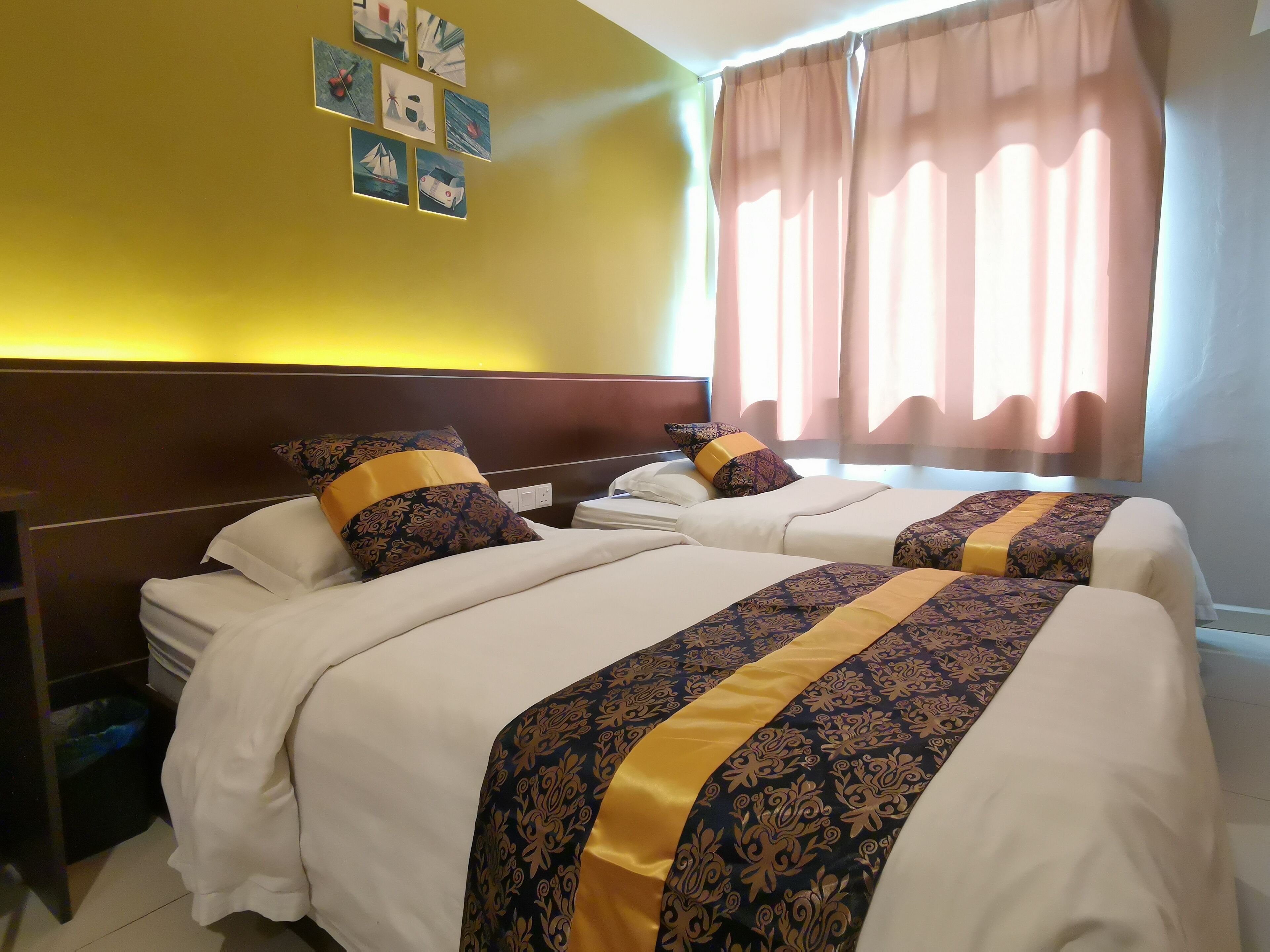 A hotel room with two beds, a headboard, a nightstand, and a window with curtains.