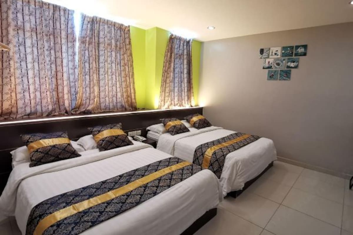 Una habitación de hotel con dos camas, un cabecero, una ventana con cortinas y una pared decorada con cuadros.