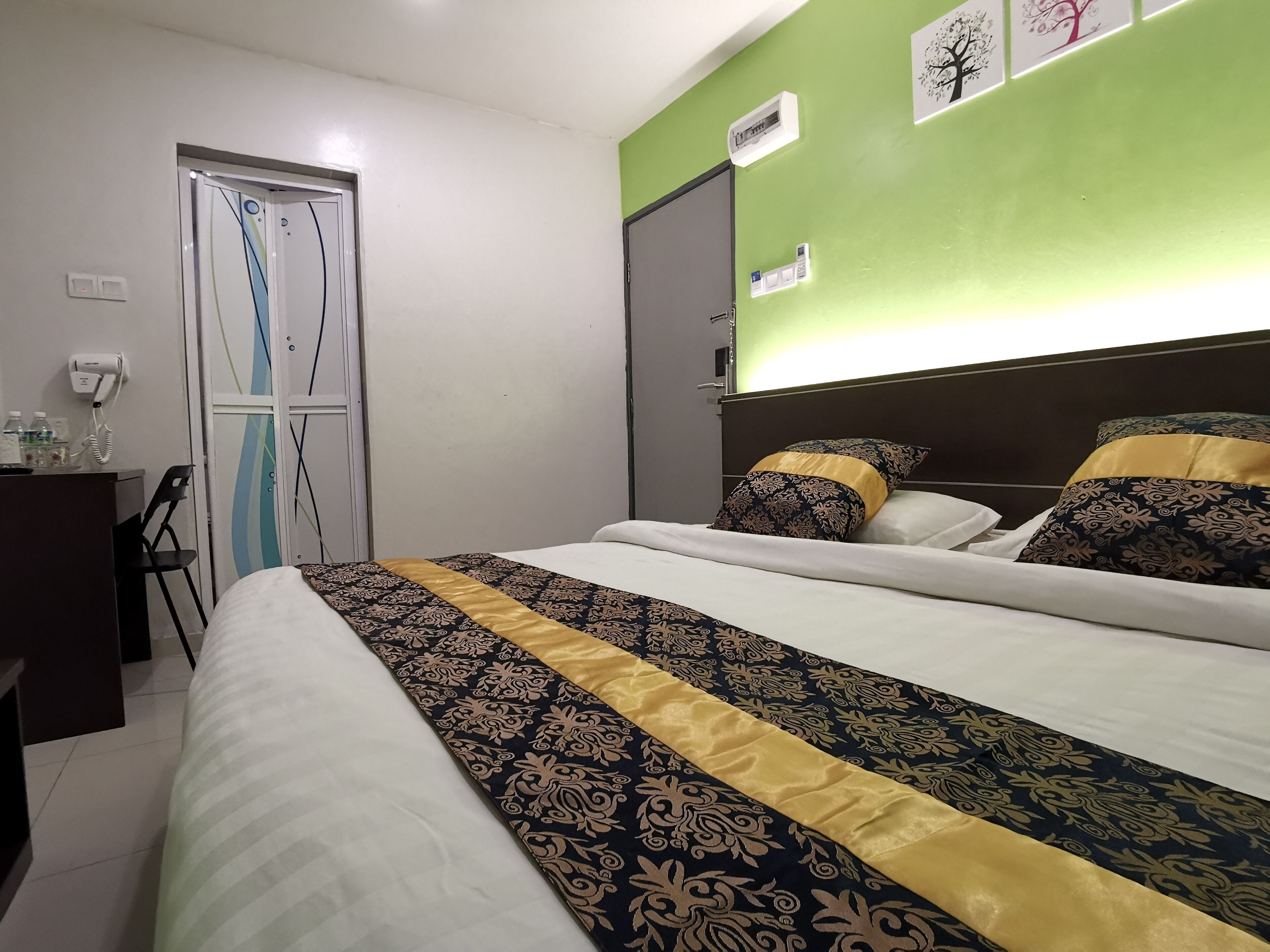 Une chambre d’hôtel avec un lit, un bureau doté d’un téléphone et de bouteilles d’eau, et une porte sur laquelle est fixé un porte-serviettes.