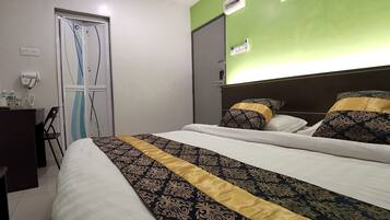 Une chambre d’hôtel avec un lit, un bureau doté d’un téléphone et de bouteilles d’eau, et une porte sur laquelle est fixé un porte-serviettes.