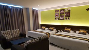 A hotel room with two beds, a sofa, and a wall with pictures. - Star Bay Hotel (Lumut)