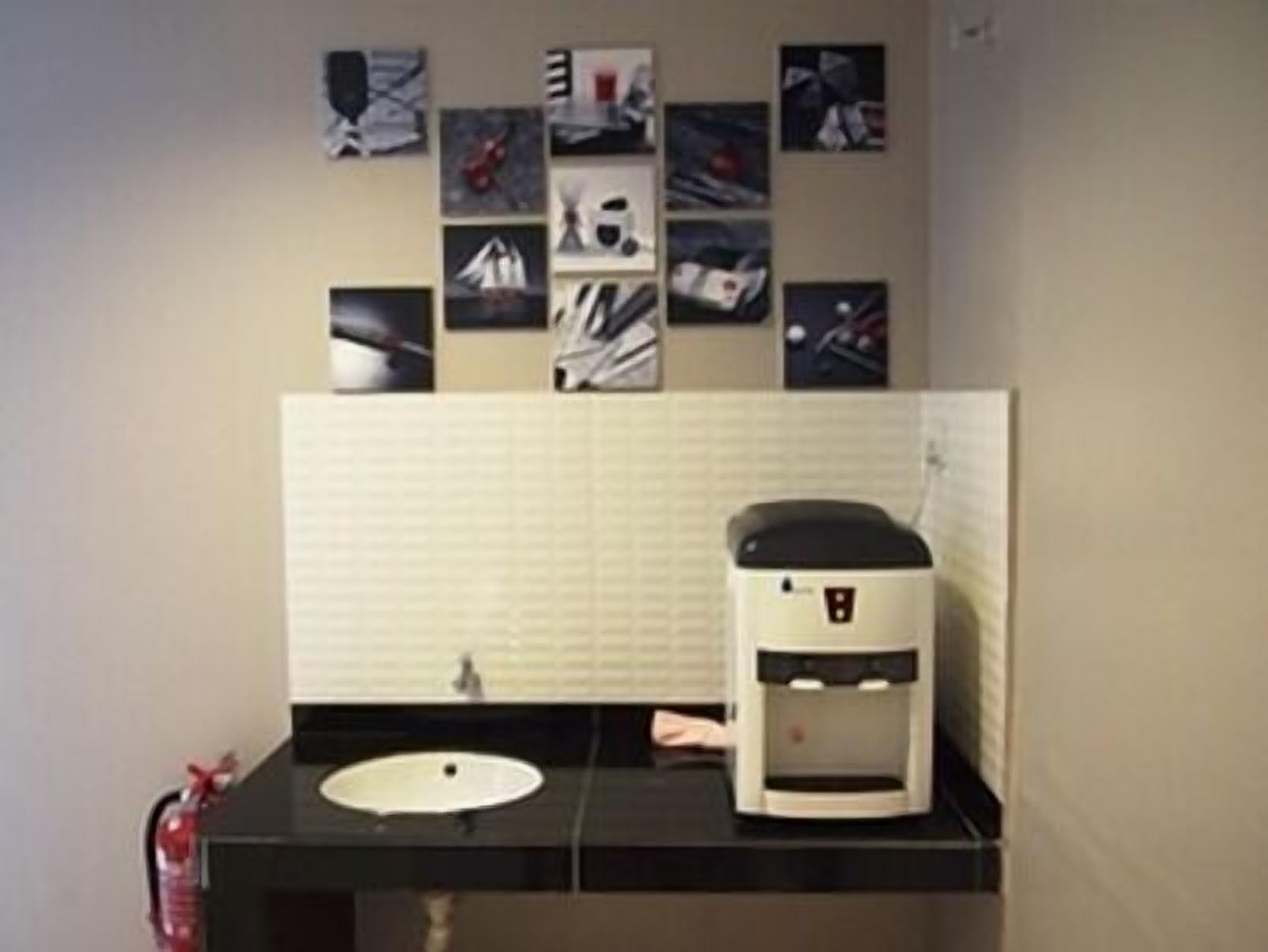 A bathroom with a black countertop, a sink, and a coffee machine.