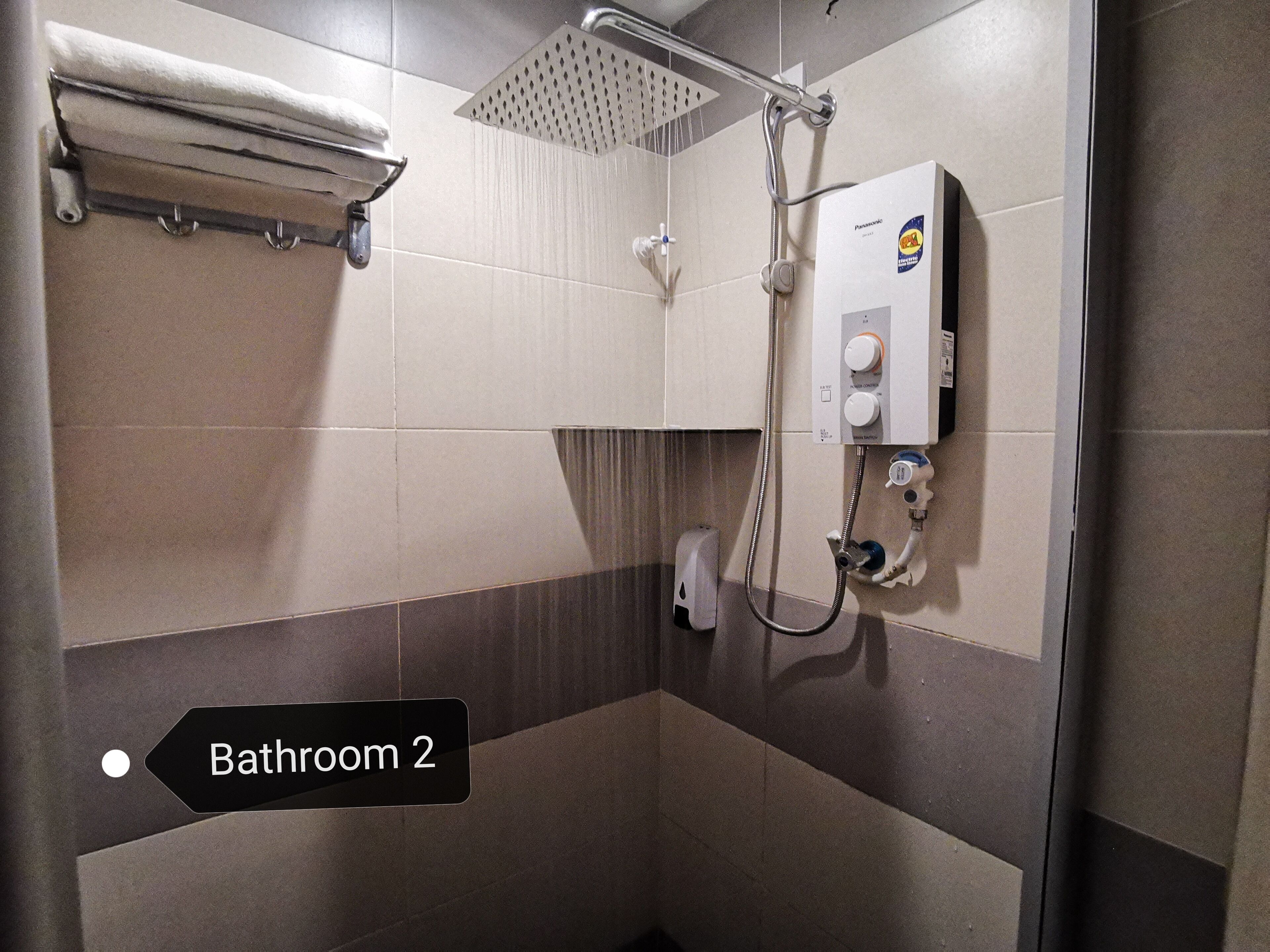 A bathroom with a shower, a towel rack, and a control panel.