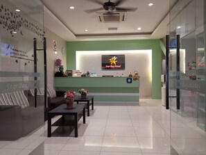 A reception area with a green wall, a StarBay Hotel sign, a reception desk, and a seating area with a sofa and tables. - Star Bay Hotel (Lumut)