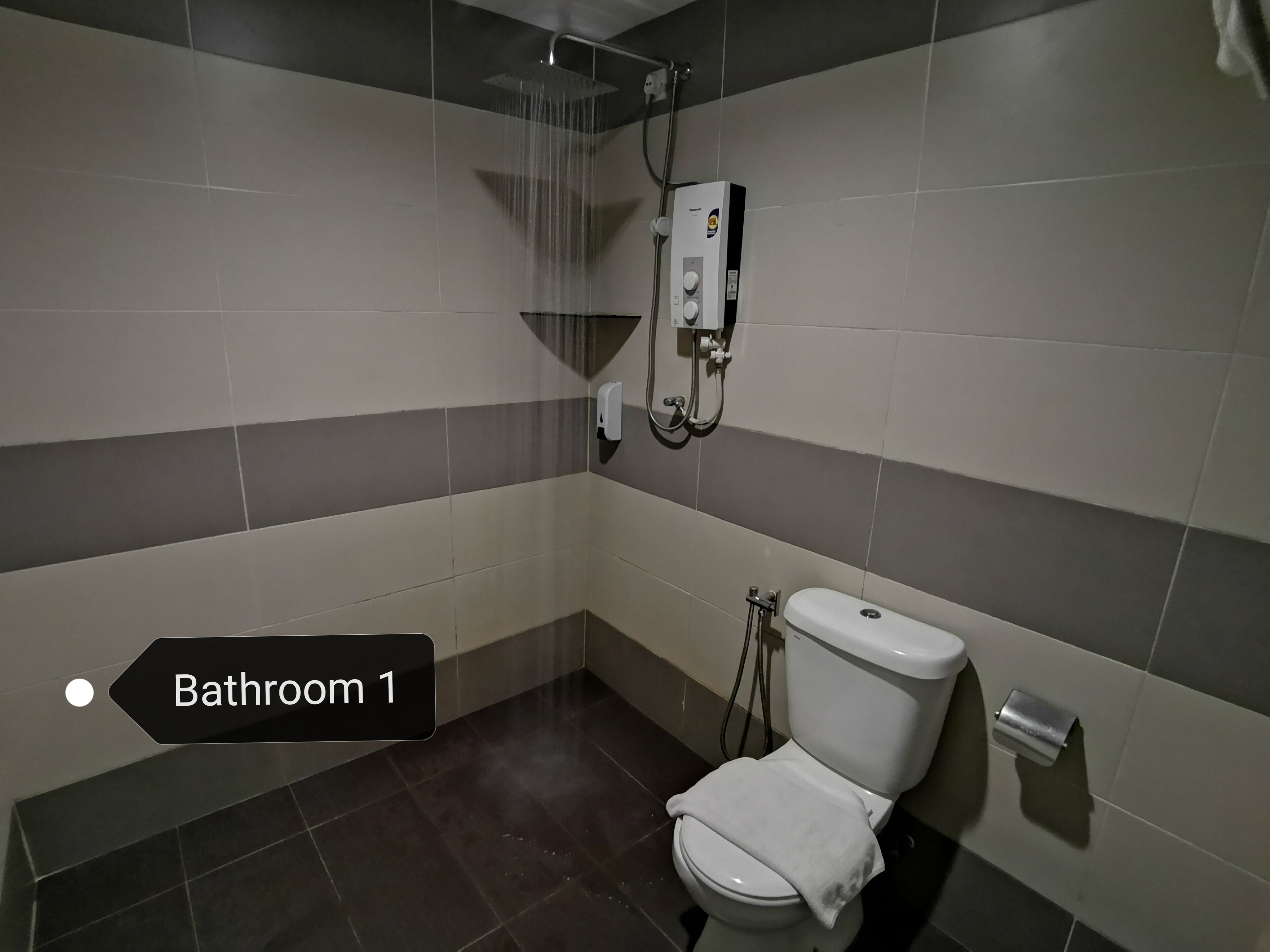 A bathroom with a shower, toilet, and hand dryer.