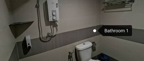 A bathroom with a toilet, a shower, and a towel rack.