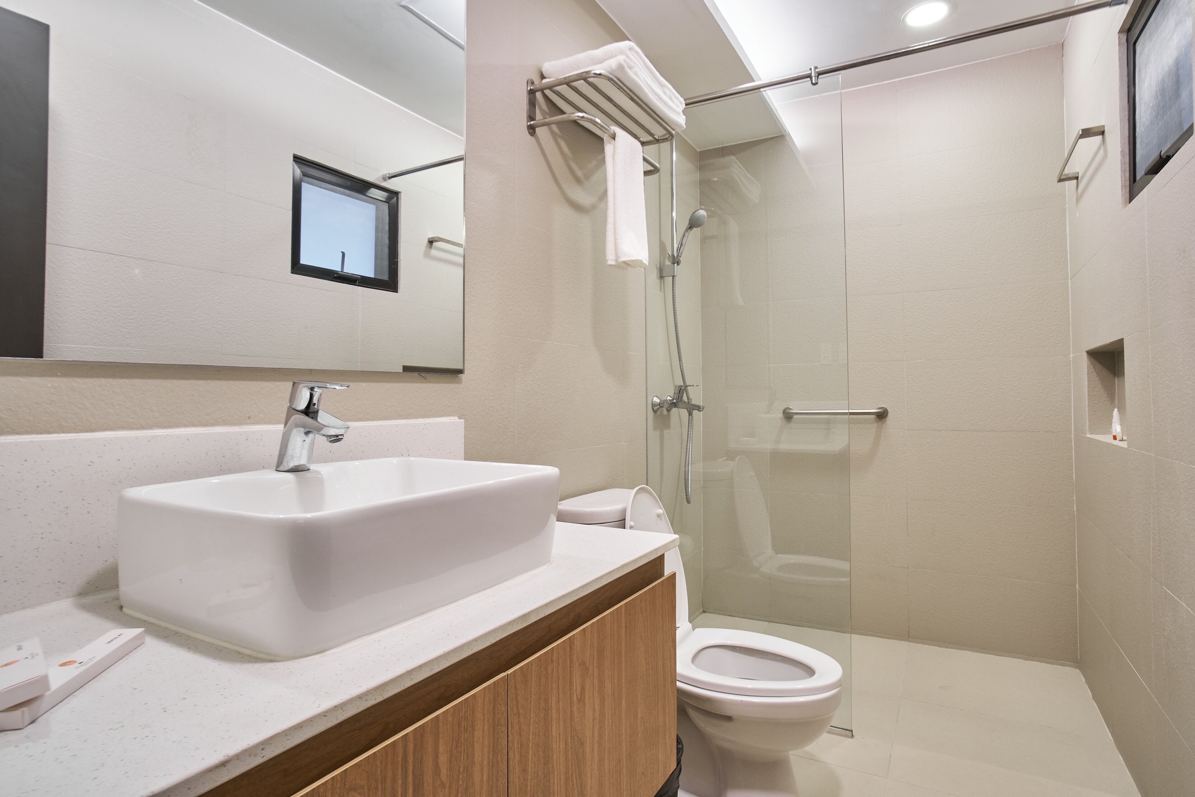 A modern bathroom with a large sink, toilet, and glass-enclosed shower.