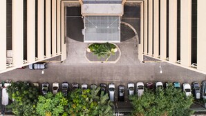 A parking area with cars and a central circular planter with greenery. - Tropicana Suites (Manila)