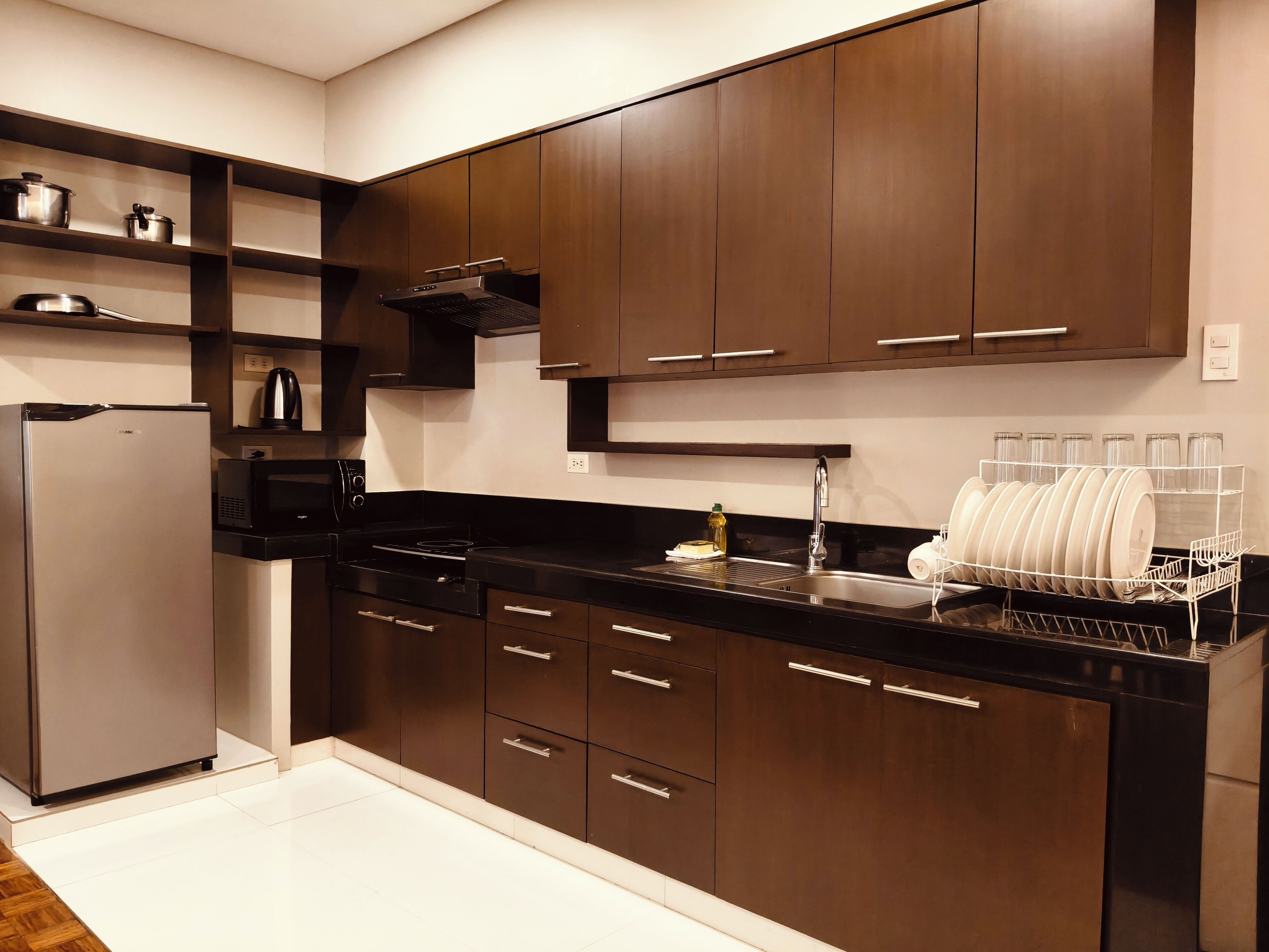 A modern kitchen with dark wooden cabinets, stainless steel appliances, and a dish rack.