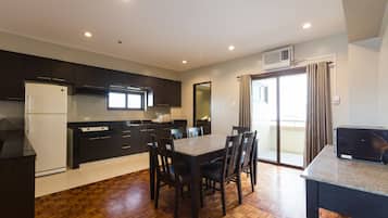 Una cocina moderna con armarios oscuros, un refrigerador blanco y un comedor con una mesa y sillas.
