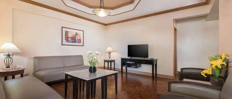 Una sala de estar con un sofá, una mesa de centro, un televisor y una lámpara.