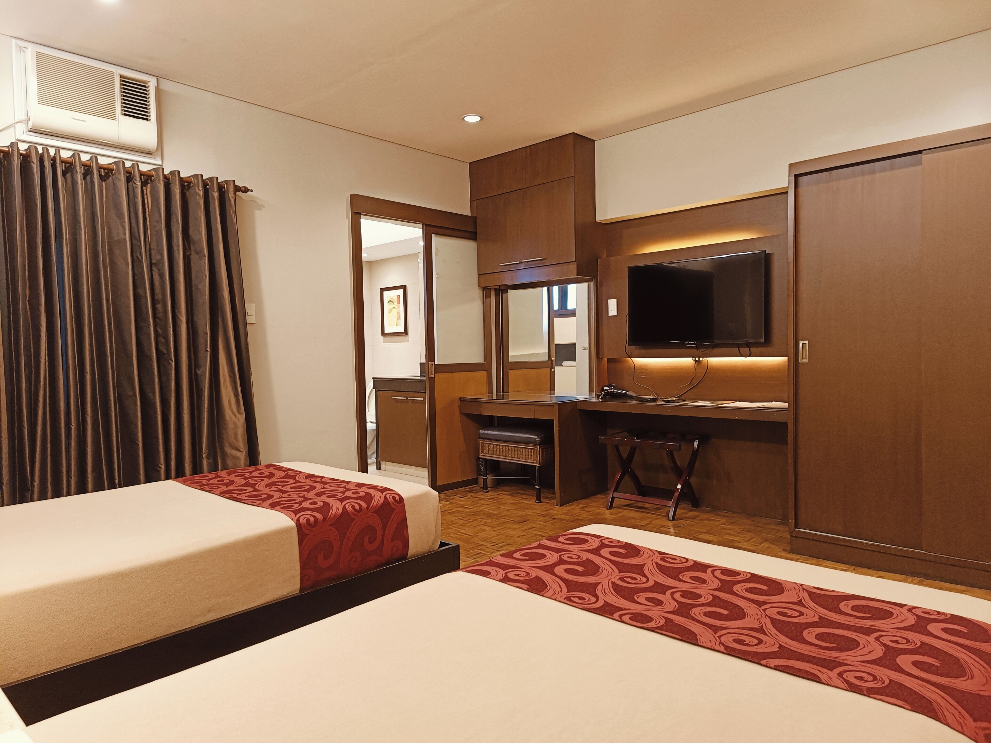 Une chambre d’hôtel avec deux lits, un bureau, une télévision et une armoire.