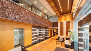 A spacious lobby with a high ceiling, a reception desk, seating areas, and a decorative wall. - Tropicana Suites (Manila)