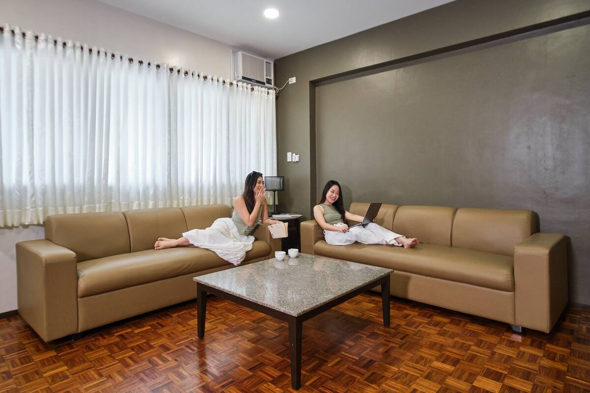 A room with two beige sofas, a coffee table, and a television on a stand.