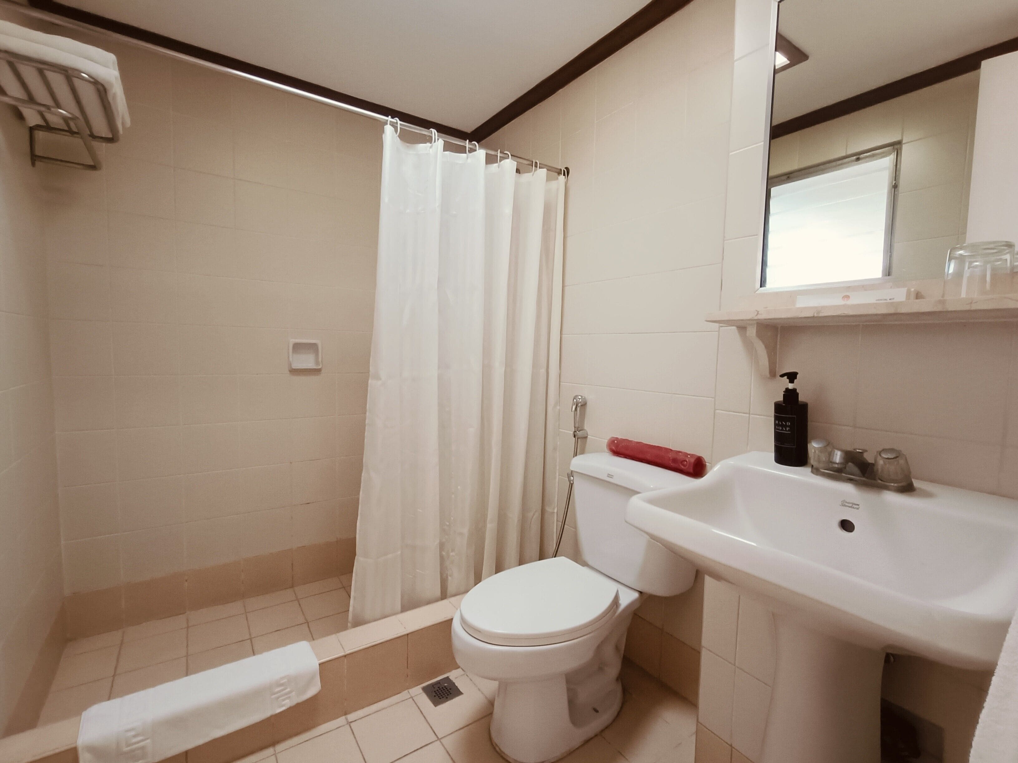 Un baño con ducha, inodoro, lavabo y un perchero para toallas.