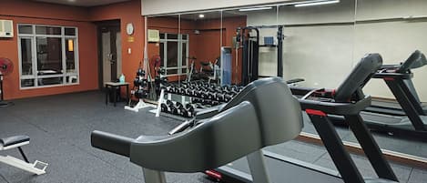 A gym with treadmills, weight benches, and free weights.