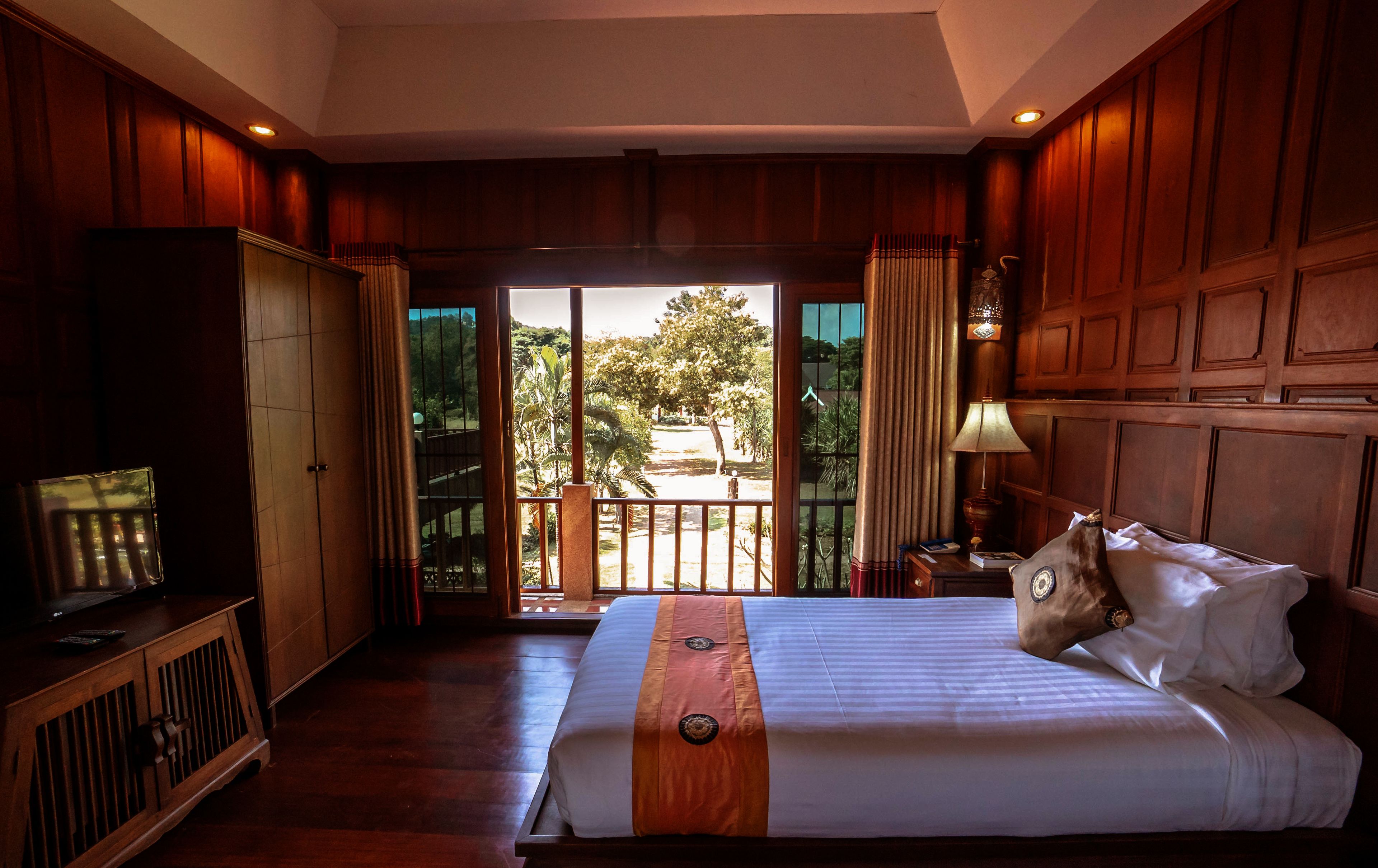 A hotel room with a bed, a desk, a TV, and a view of the outdoors.