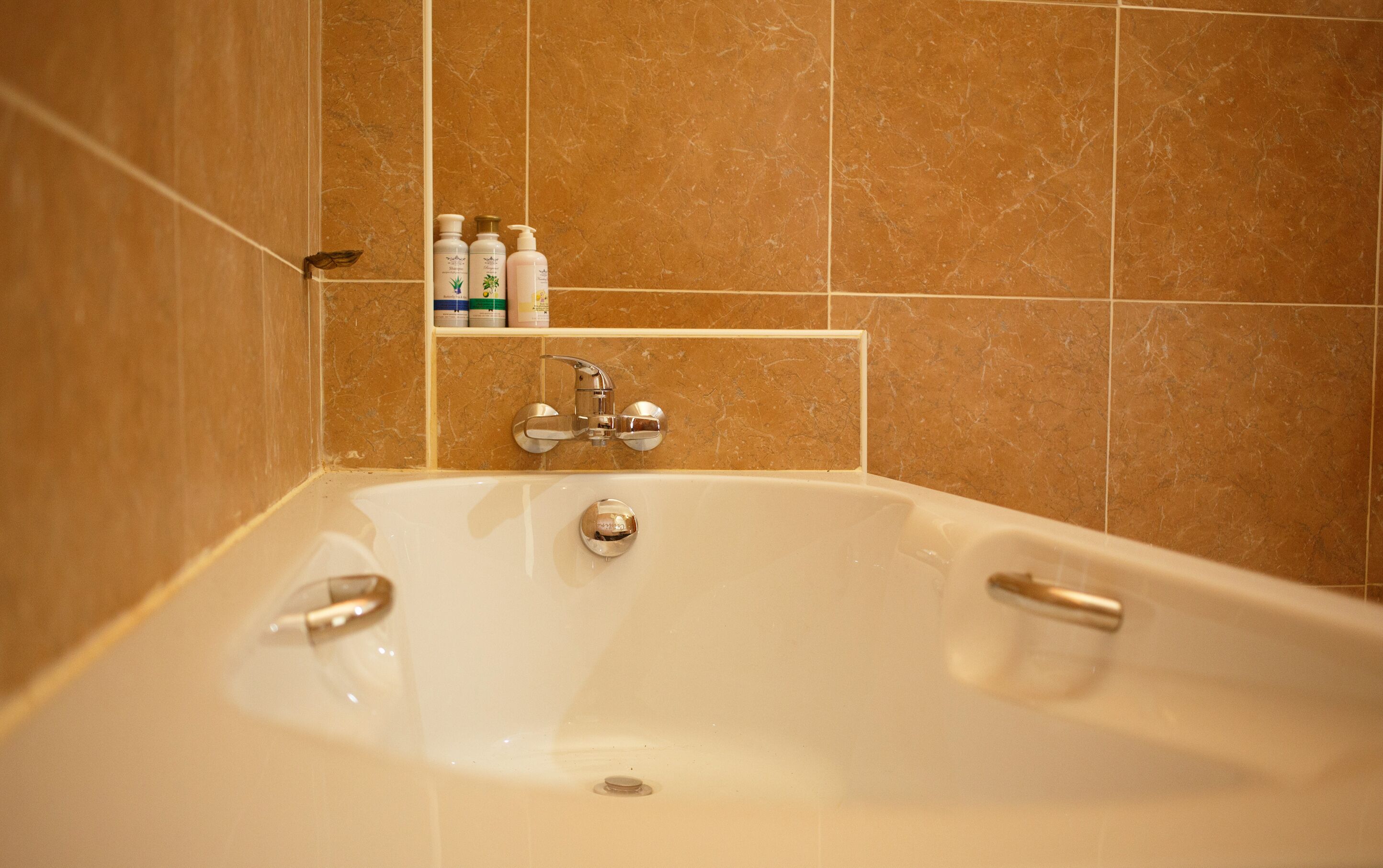 Un baño con bañera, ducha y estante con artículos de aseo.