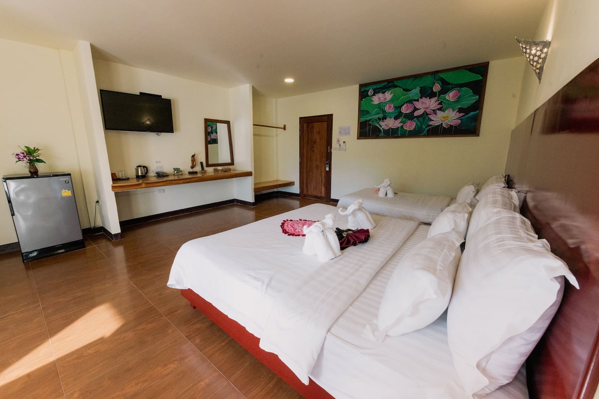 Habitaci ón de hotel con una cama grande, una kitchenette pequeña, un televisor y un cuadro de flores en la pared.