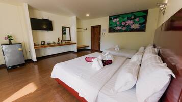 A hotel room with a large bed, a small kitchenette, a TV, and a painting of flowers on the wall.