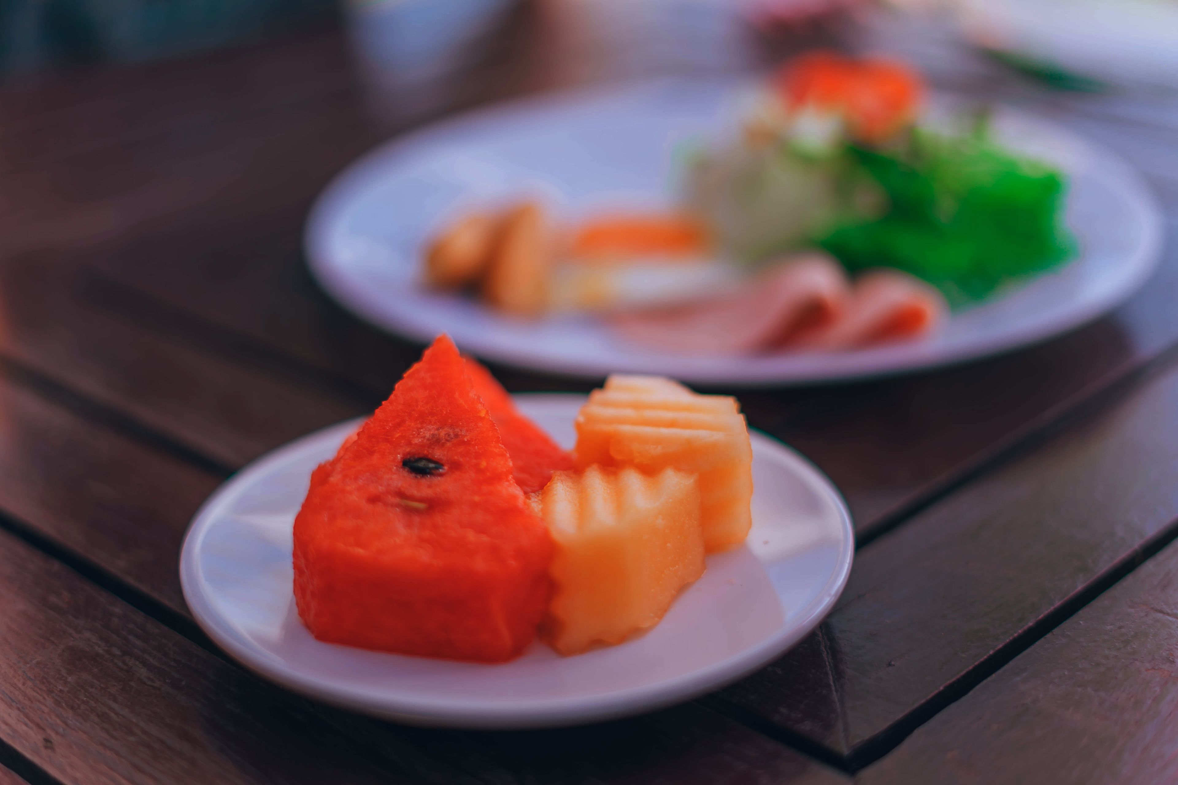 A plate with a red and yellow food item on a wooden table.