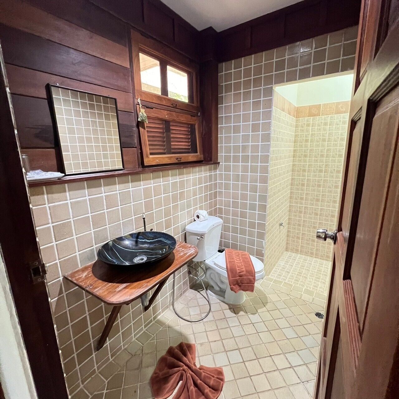 A compact bathroom with a toilet, a sink with a basin, a towel rack, and a window above the sink.