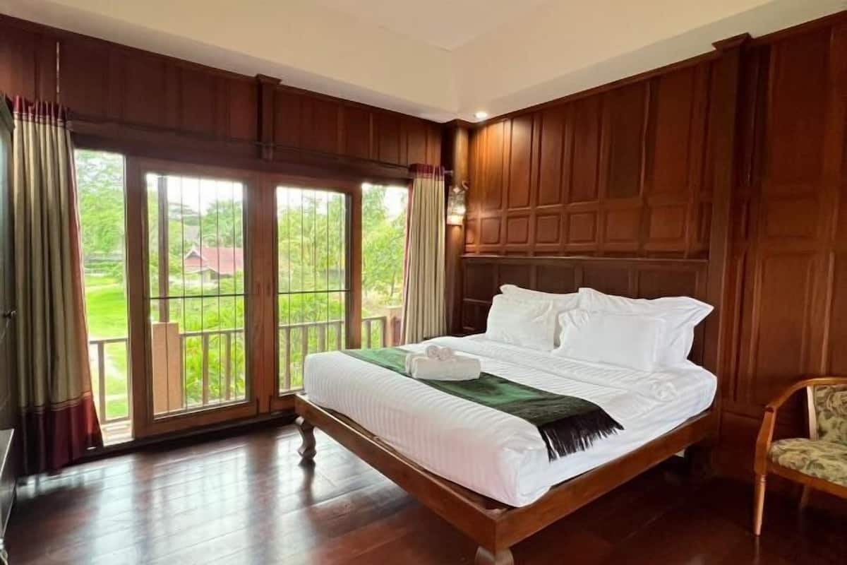 Un dormitorio amplio con una cama grande, paneles de madera y vistas a través de una puerta corredera de vidrio.