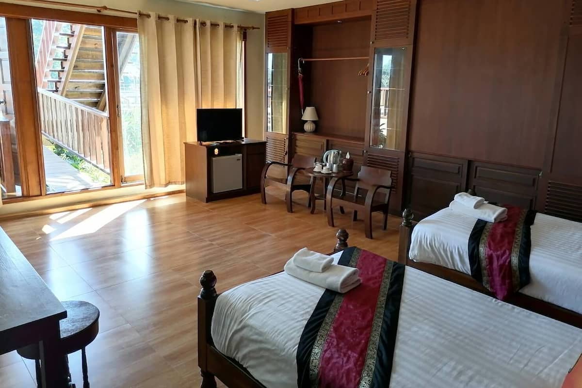 Habitación de hotel con dos camas, un escritorio con televisor, una silla y una escalera que da al exterior.