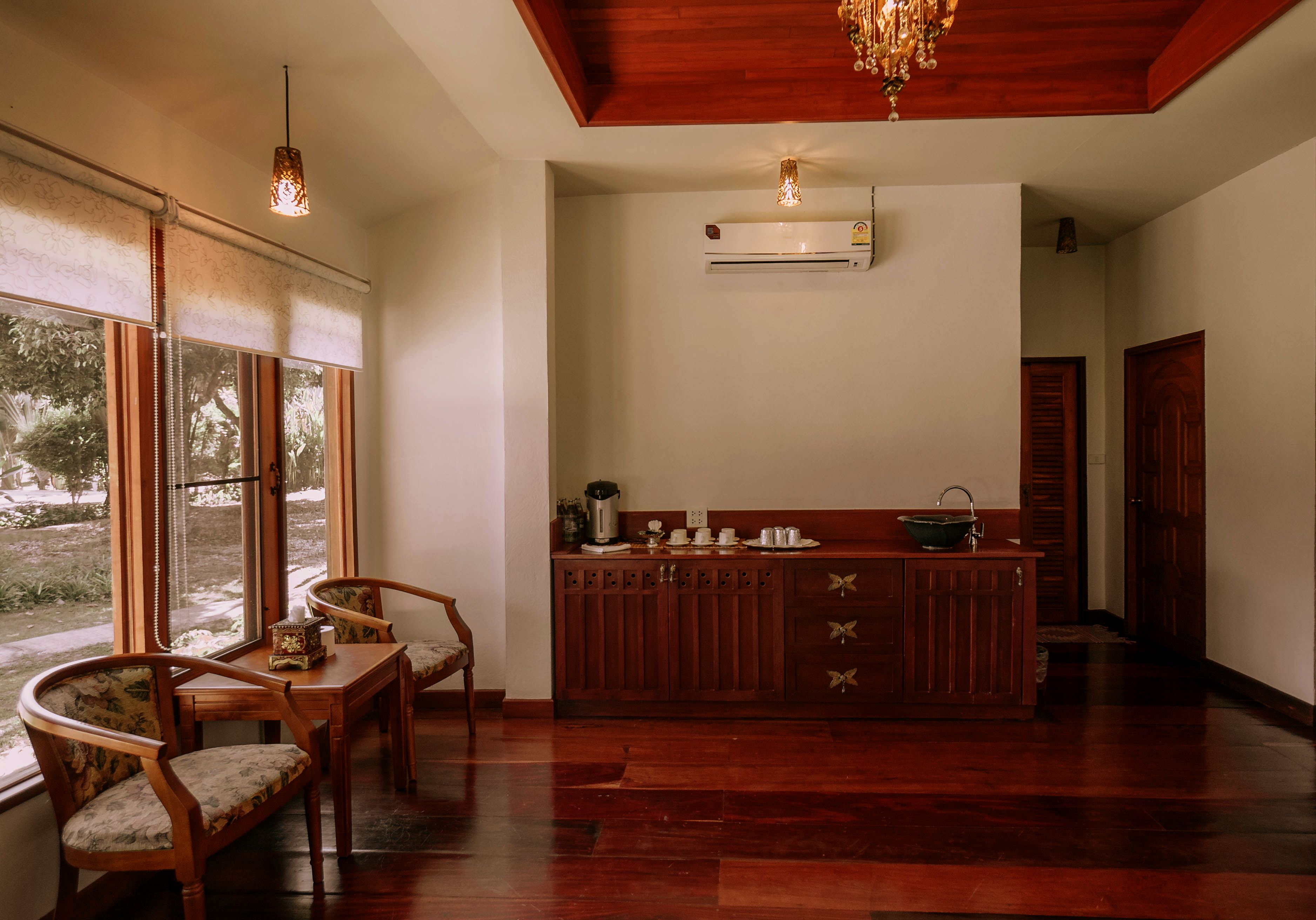 Uma área de refeições de madeira com mesa e cadeiras, bancada de cozinha com armários e um aparelho de ar condicionado na parede.