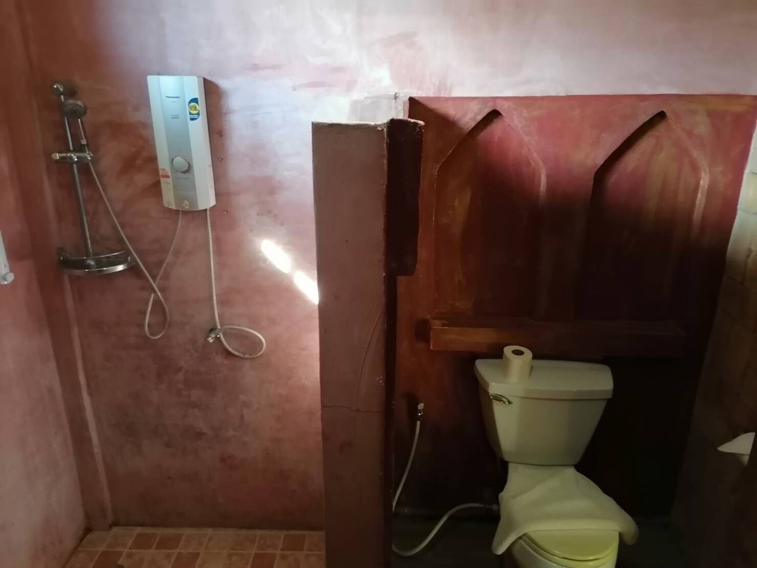 A small bathroom with a toilet, a shower, and a water heater.