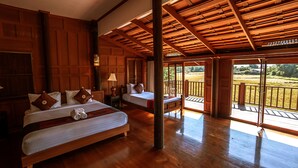 Une chambre d’hôtel avec deux lits, un plancher en bois, une grande fenêtre et un balcon.