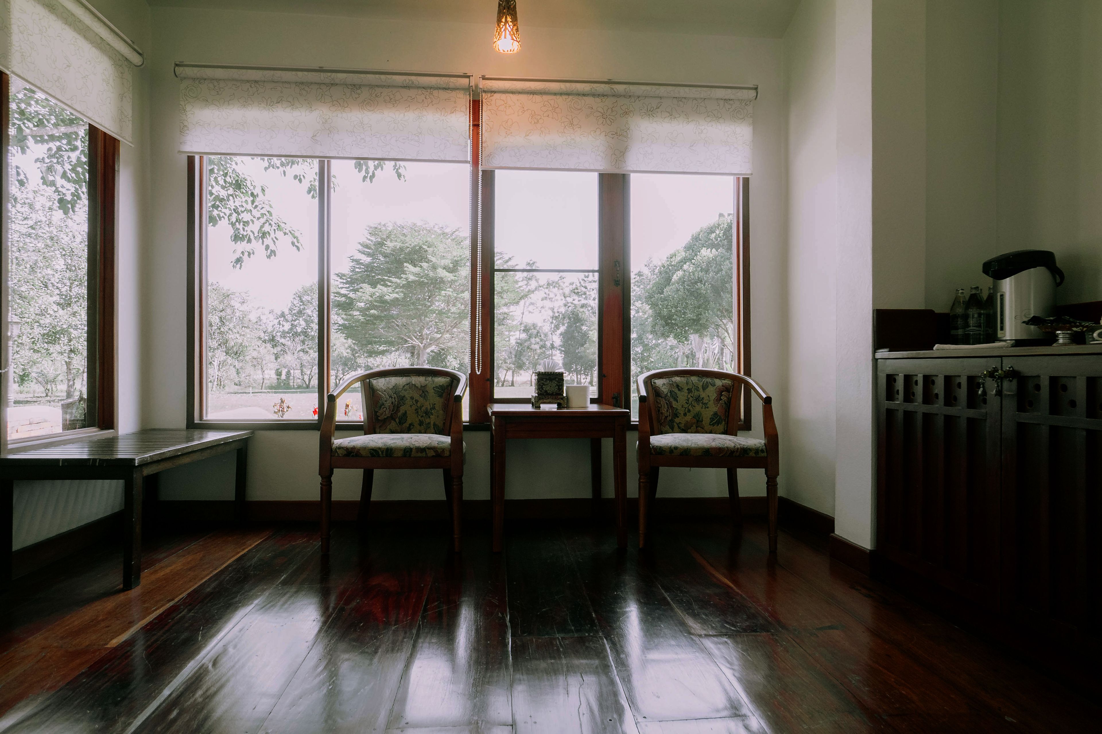A room with a large window, two chairs, a small table, and a radiator.