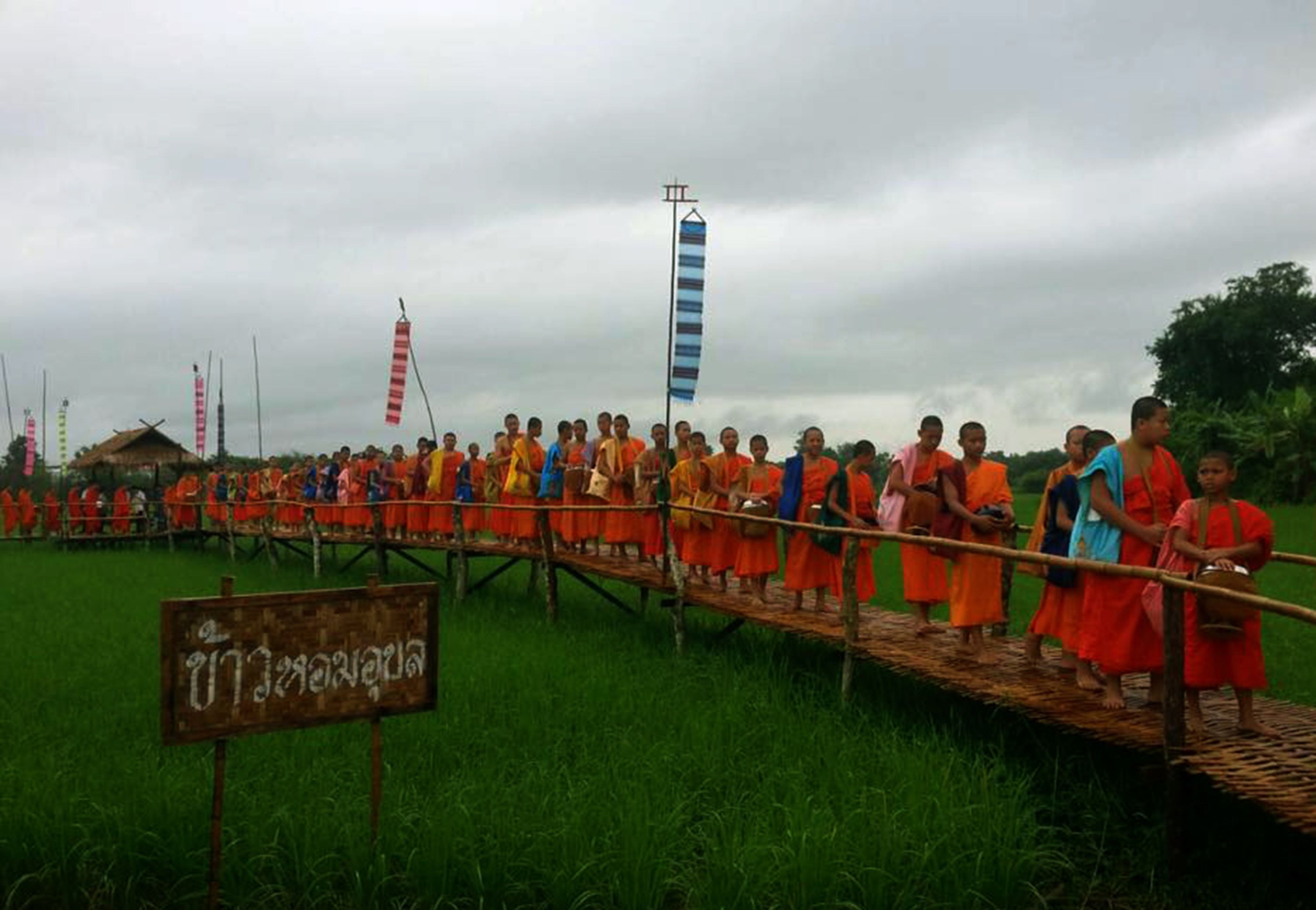 Un grupo de personas sobre un puente de madera sobre un campo.