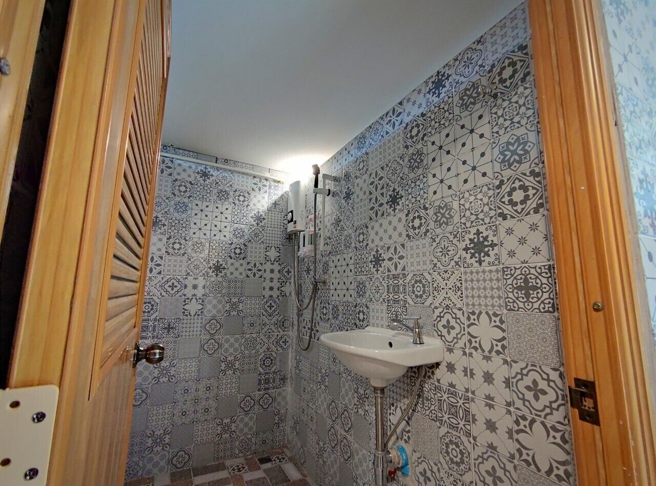 A bathroom with patterned tiles, a sink, and a shower.