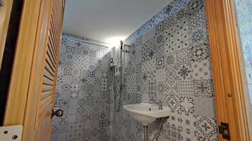 A bathroom with patterned tiles, a sink, and a shower.