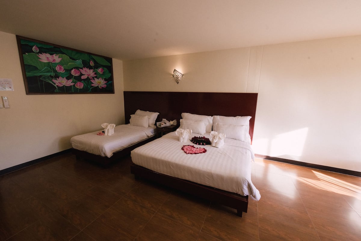 Habitación de hotel con dos camas, un cuadro de flores en la pared y una mesita de noche con lámpara.