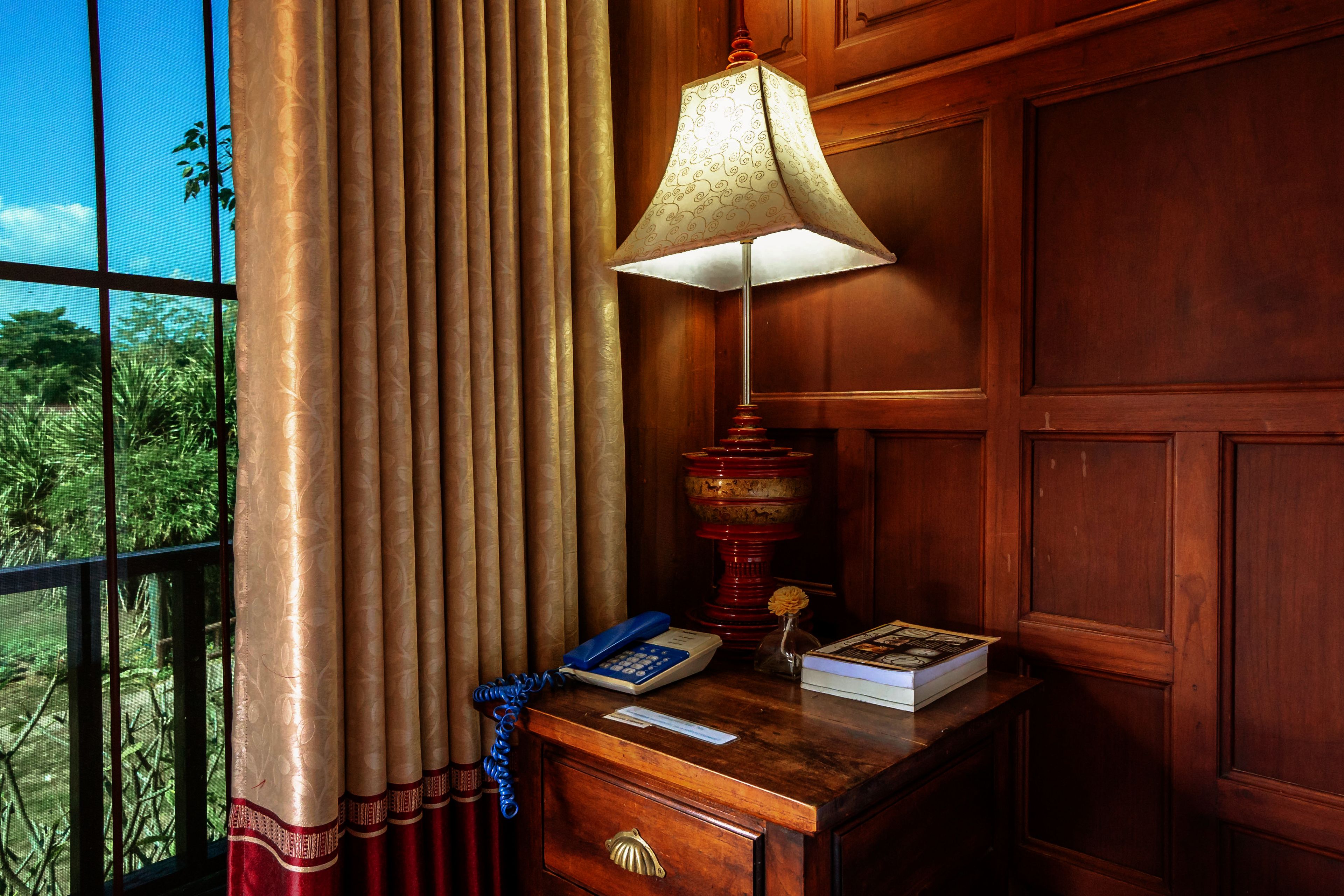 A wooden desk with a lamp, a telephone, and a book.