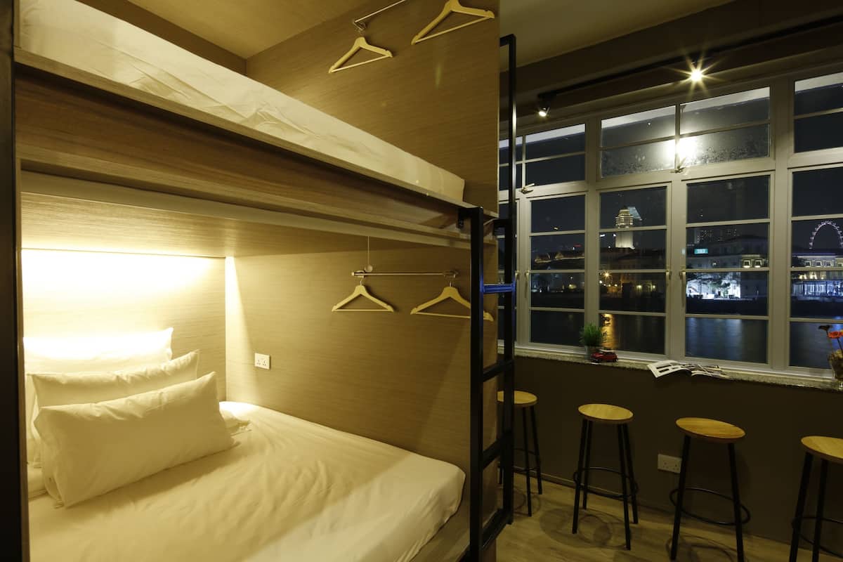 Ein Hotelzimmer mit einem Bett, einem Fenster mit Blick auf ein Riesenrad und drei Barhocker.