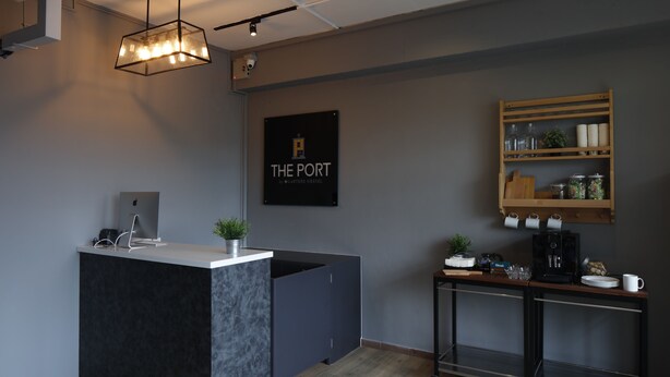 A modern kitchen with a central island, a coffee station, and a sign reading "THE PORT".