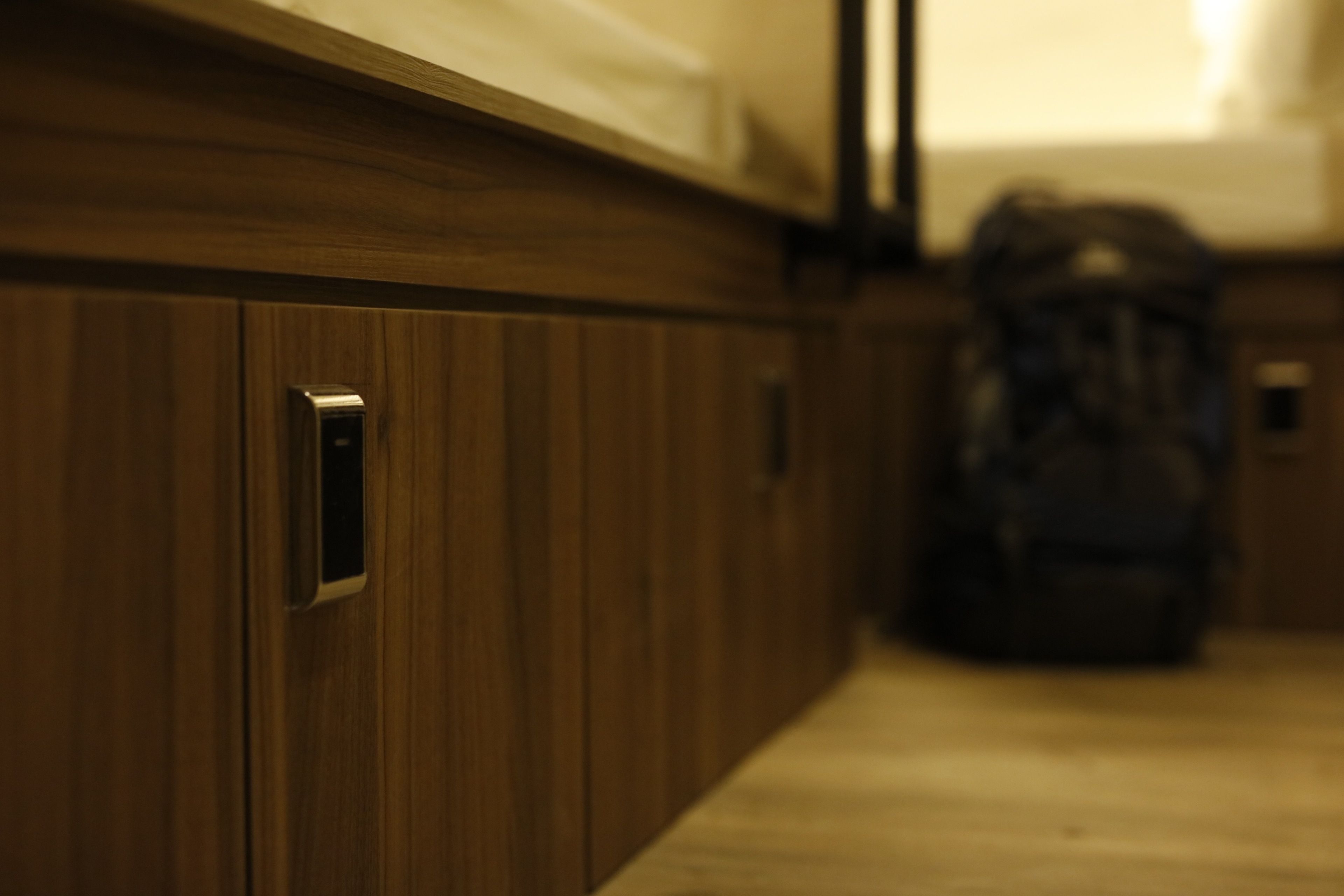 Pared de madera con una puerta y un pequeño dispositivo electrónico, posiblemente un termostato o intercomunicador, montado en ella.