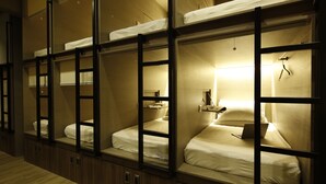 A row of bunk beds with individual compartments, each with a small shelf and a hanging light.