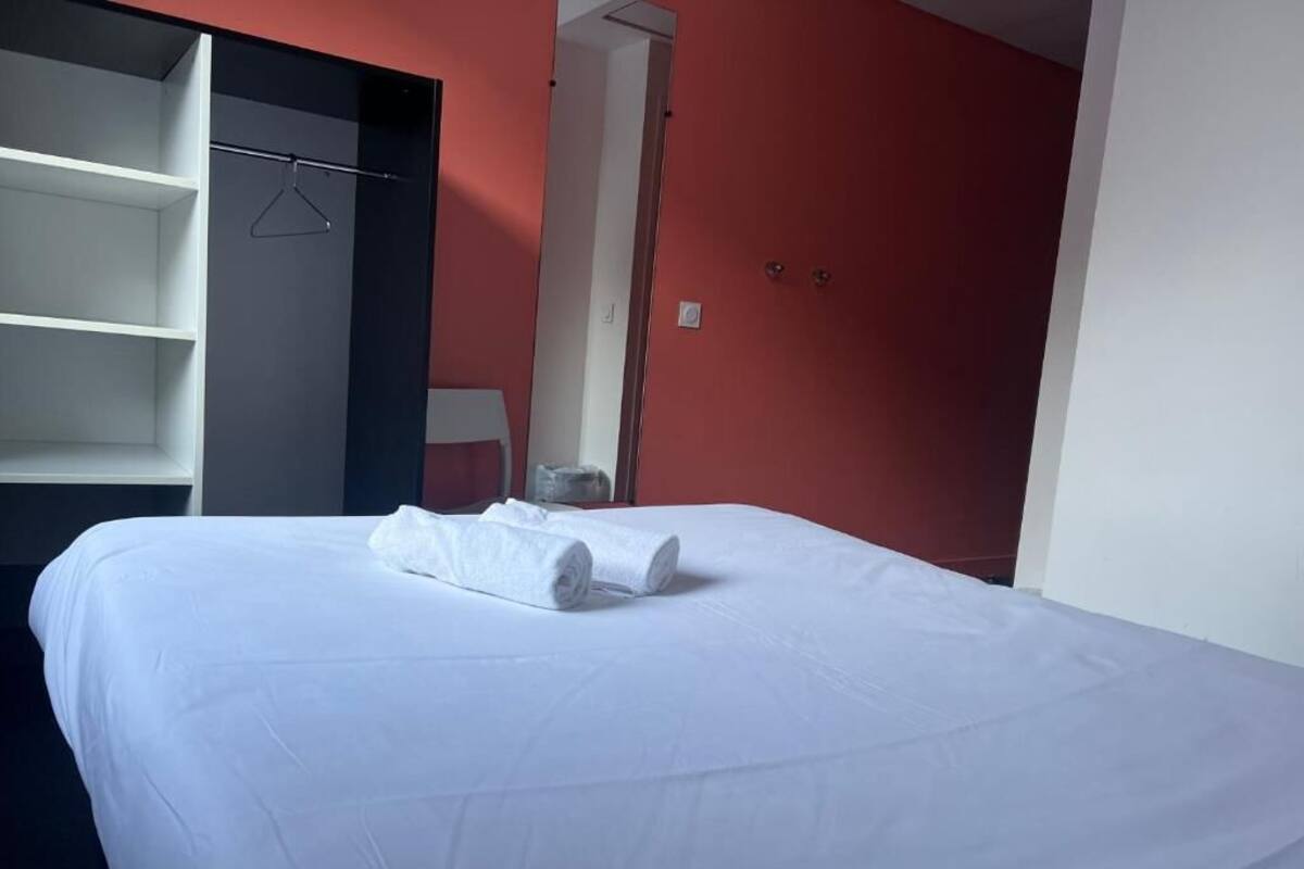 Una habitación de hotel con una cama, un armario y una pared roja.