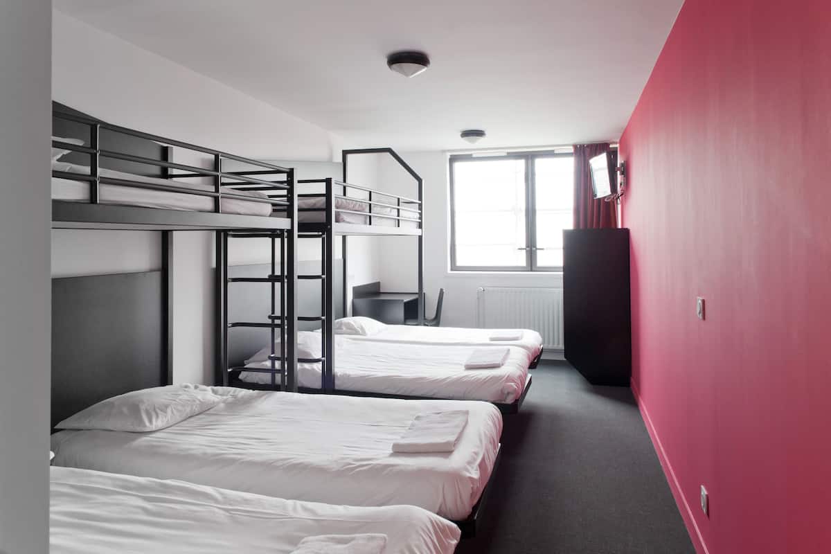 Un dormitorio con literas, un escritorio, una silla y una ventana con cortinas.