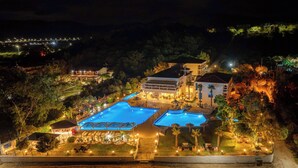 Een resort met meerdere zwembaden, een goed verlicht buitengebied en verschillende gebouwen.