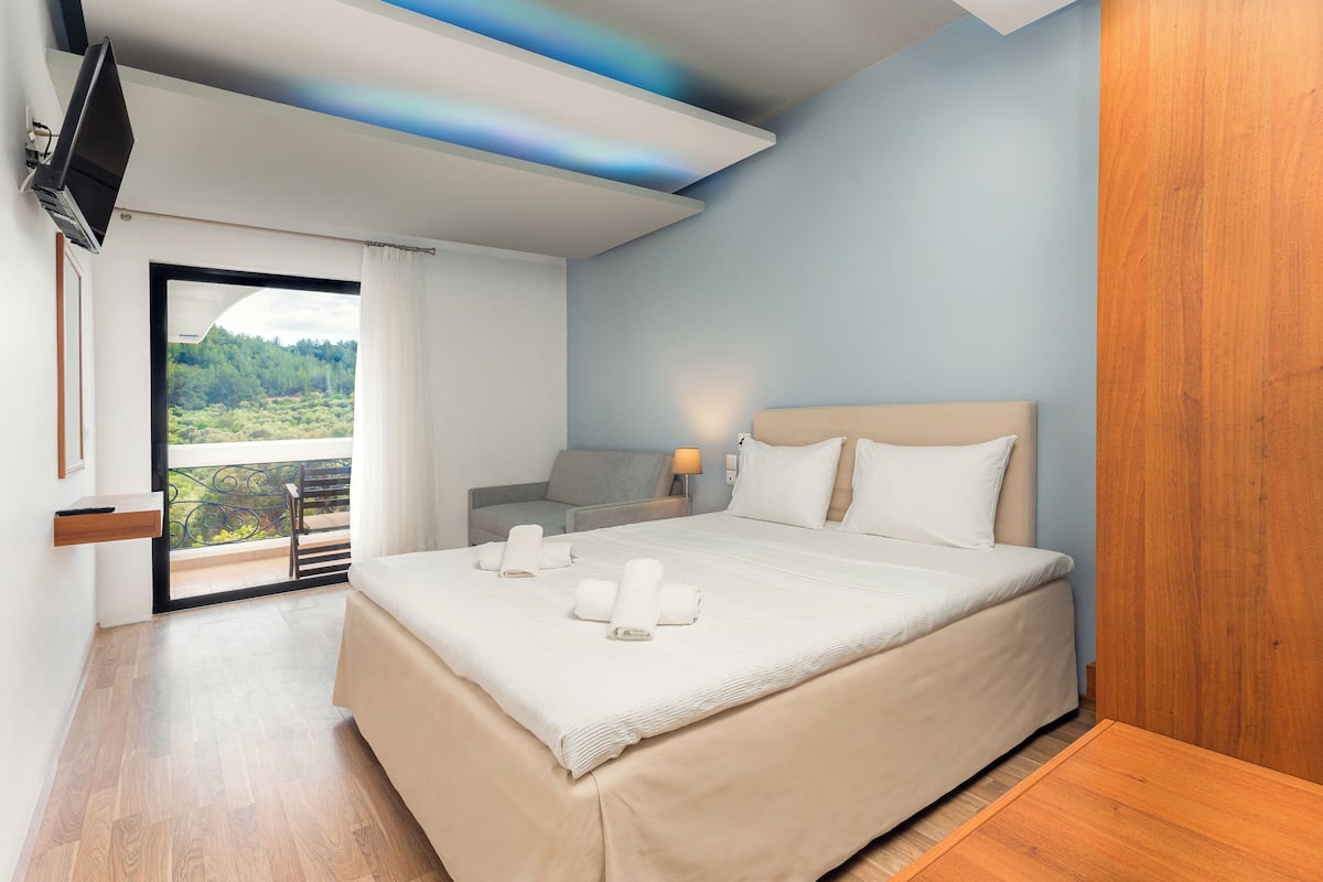 Ein Schlafzimmer mit Bett, Fernseher, Balkon und Aussicht sowie einer Couch.