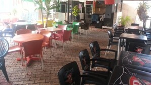 An outdoor seating area with tables and chairs, some with umbrellas. - Definite Destiny Asaba (Asaba)