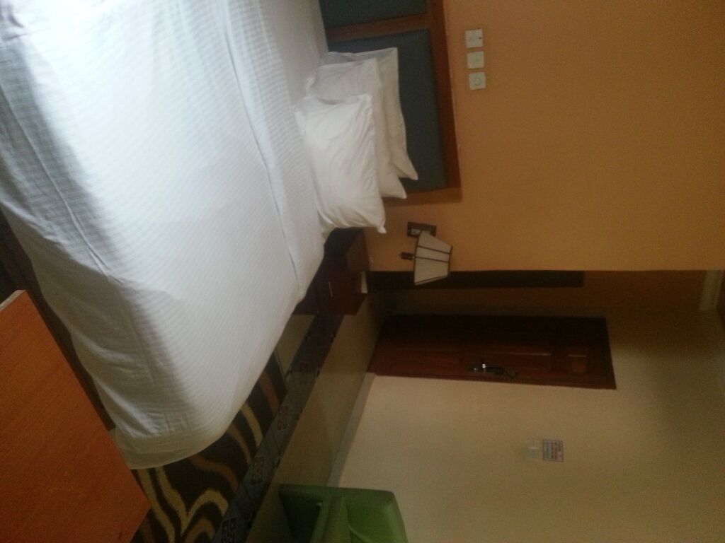 A room with a bed, a small table, and a wall-mounted shelf.
